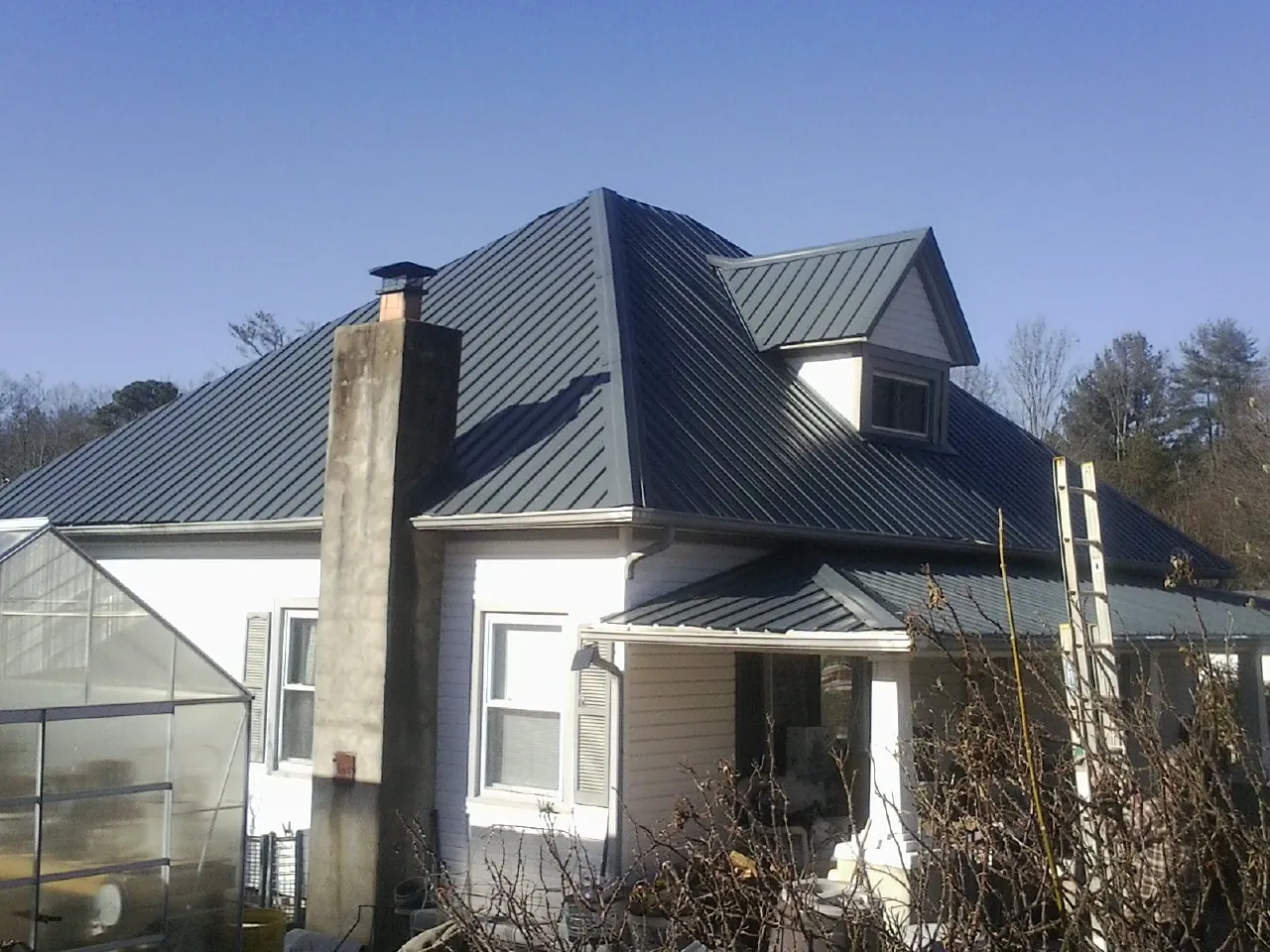 Dark blue standing seam metal roof on a white farmhouse with dormer — Slate & Tile Roof Repair by Roofing Brothers in Blue Ridge