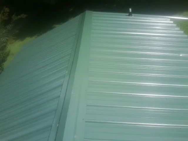 New green metal panels meeting at the ridge of a roof — Flat Roof Repair work by our crew in Blue Ridge