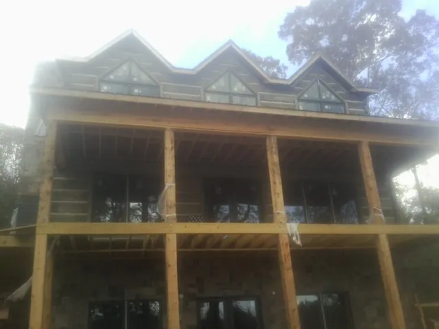 Dormers and porch framing on a large log home under construction — Roof Coating work by our crew in Blue Ridge